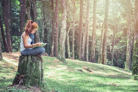 Premium Photo Young Woman Reading Book While Sitting On Tree Stump In