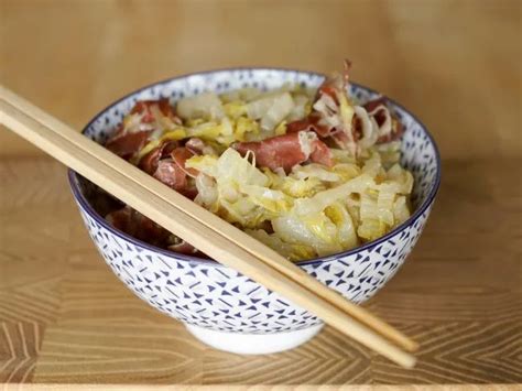 A Bowl Filled With Food And Chopsticks On Top Of A Wooden Table