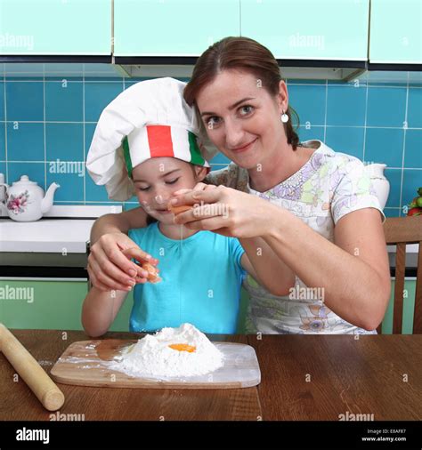 Woman and girl in Italian chef hat break egg into flour Stock Photo - Alamy