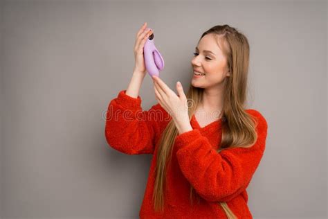 A Pretty Caucasian Girl In A Red Sweater Smiles While Holding A Lilac Dildo A Massager For Sex