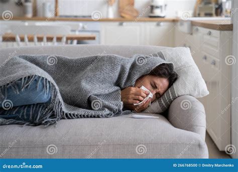 Sick Unhealthy Woman Lying Under Blanket On Sofa Coughing And Sneezing