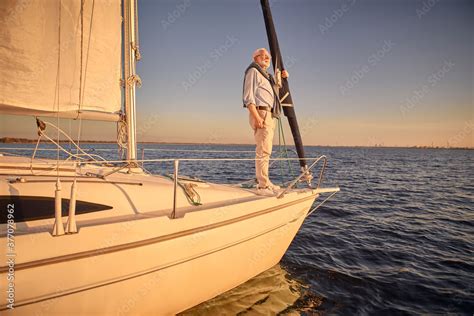 Senior Man Standing On The Side Of A Sailboat Or Yacht Deck Floating In