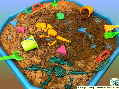 A Blue Tray Filled With Sand And Plastic Toy Dinosaurs In Its Center Area