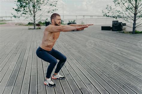 La Foto Completa Del Hombre Activo Hace Poses De Ejercicio En Cuclillas