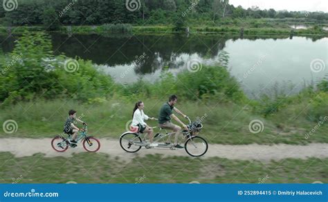 Married Couple With A Child Rides A Two Person Tandem Bike Along The