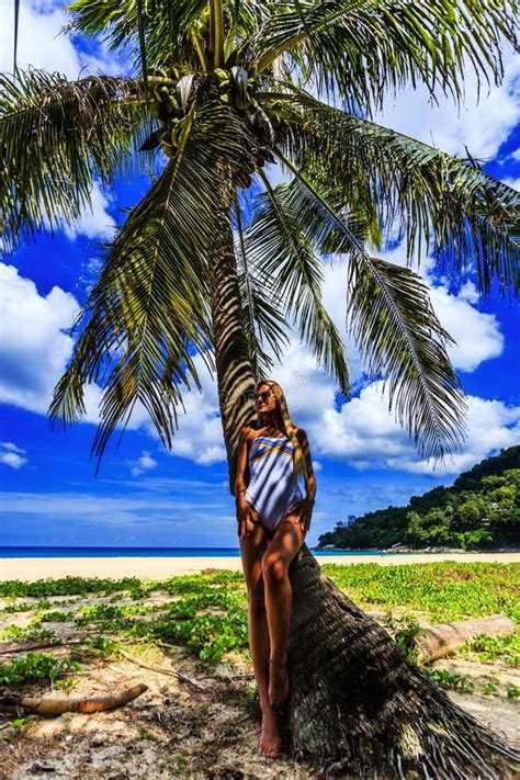 Mujer En El Bikini Blanco Que Presenta En La Palmera Foto De Archivo