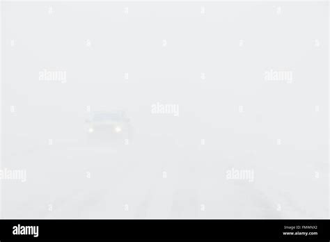 A White Truck Driving In Zero Visibility During Whiteout Conditions