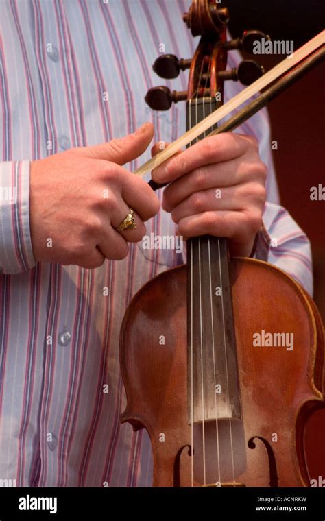 Man In Striped Shirt Holding Violin And Bow On Stage At Irish