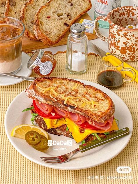 A Plate With A Sandwich On It Next To Some Lemons And Other Food Items