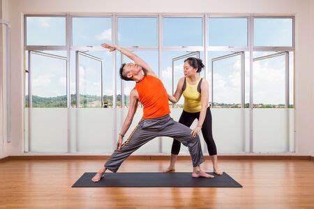 Yoga Instructor Guiding Student Perform Extended Side Angle Pose Or