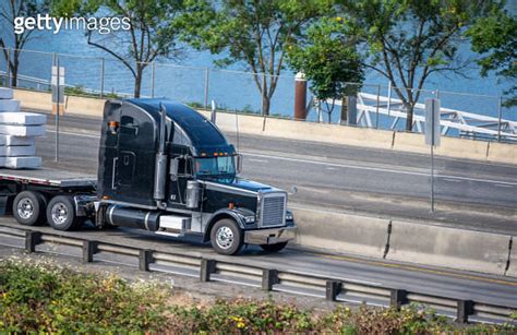 Classic Big Rig Black Semi Truck Transporting Packed Cargo On Flat Bed