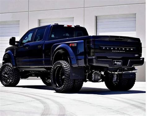 A Large Black Truck Parked In Front Of A Garage