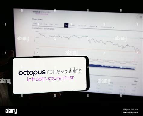 Person Holding Mobile Phone With Logo Of Octopus Renewables