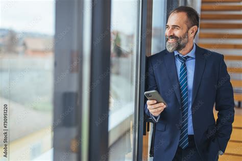 Smiling Mature Businessman Holding A Smartphone In An Office