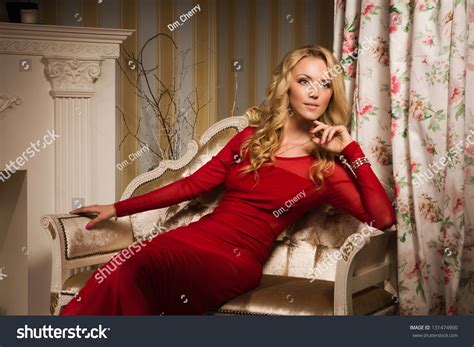 Beautiful Blonde In A Red Dress Sitting On The Couch In The Vintage