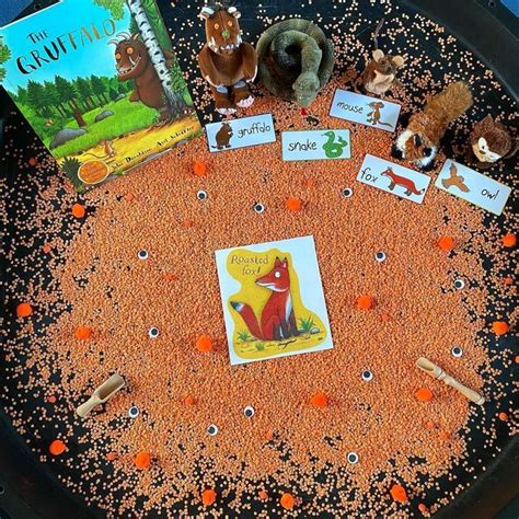 There Are Many Books And Toys In The Sand On The Table With Orange