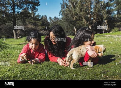 Mère avec ses deux filles jouant avec un chiot Golden Retriever dans