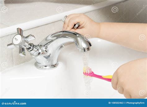 Child Rinsing Toothbrush In Running Bathroom Sink Water Stock Image