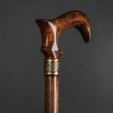 An Old Wooden Walking Stick With White And Gold Decoration On The End