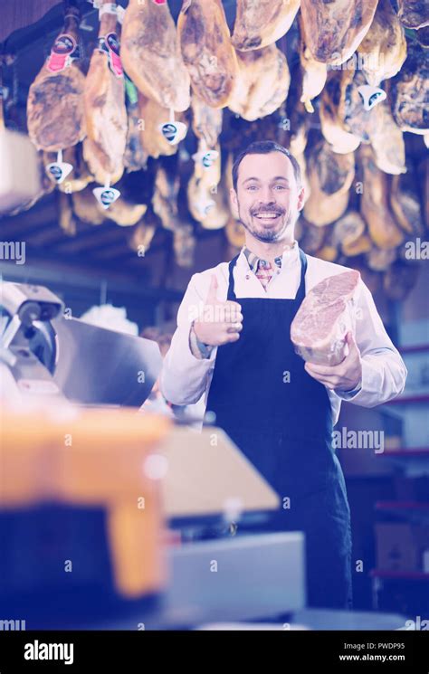 Male Shop Assistant Demonstrating Piece Of Meat In Butchers Shop Stock