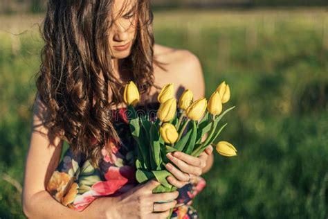 Portrait Of Beautiful Brunette Women In Field Holding Flowers Stock