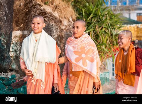 Three Young Female Buddhist Monks In Orange Garments Strolling On The