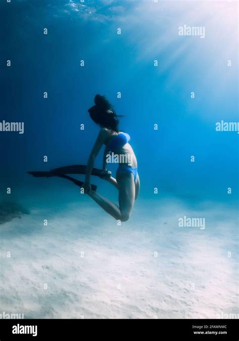 Free Diver With Fins Posing Underwater Over Sandy Bottom In Tropical