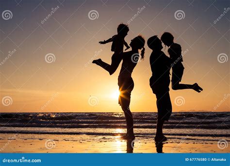 Silueta De La Familia Feliz Que Juega En La Playa En El Sunse Foto De