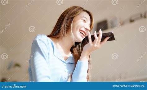 Happy Young Asian Woman Speaking On Mobile Phone At Home Stock Photo