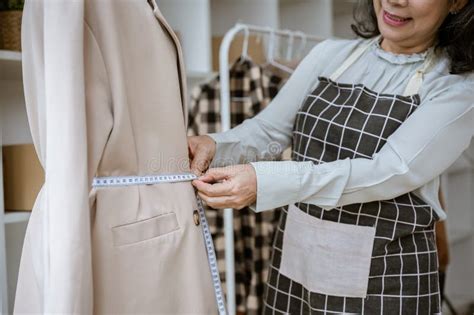 An Attractive Mature Asian Female Tailor Is Measuring And Adjusting The