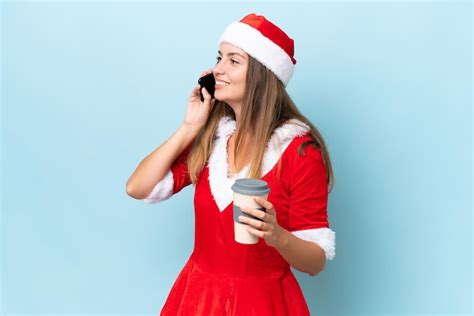 Jovem mulher caucasiana vestida como mamãe noel isolada em fundo azul