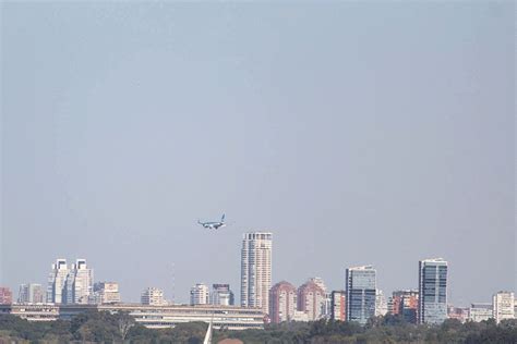 An Airplane Is Flying Over The City With Tall Buildings In The Backgrouds