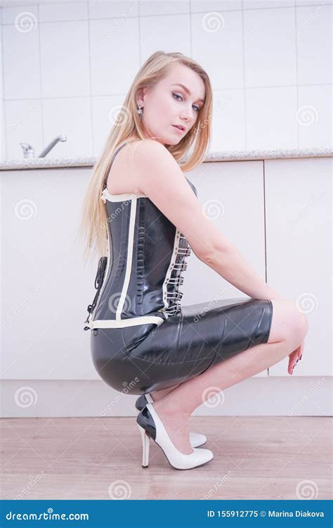 Beautiful Blonde Vamp Mistress In Black Fetish Corset On White Home