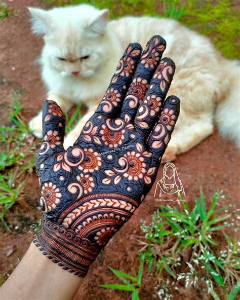 A Cat Sitting On The Ground Next To A Person S Hand With Henna Tattoos