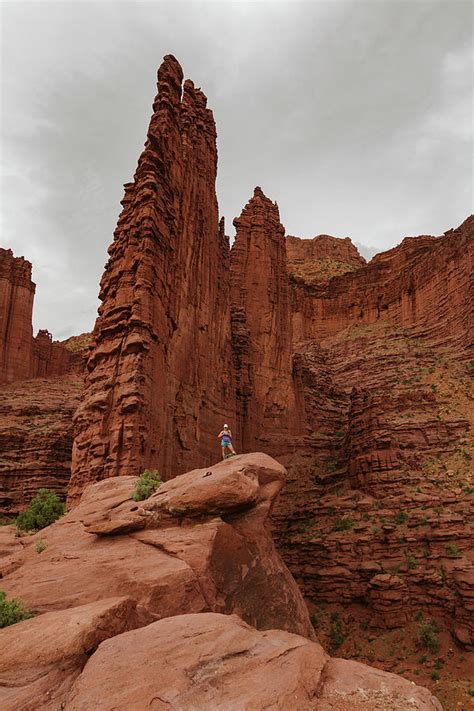 Hiker Stands Under Fisher Towers On A Hike Outside Of Moab Utah