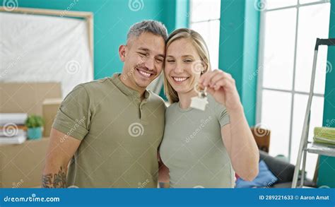 Man And Woman Couple Hugging Each Other Holding Keys At New Home Stock