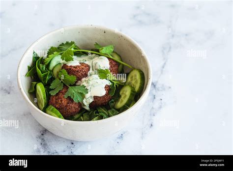 Green Salad With Falafel Tahini Dressing In A White Bowl On A White
