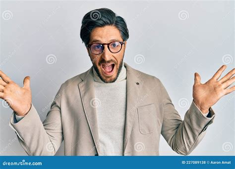 Young Hispanic Man Wearing Business Jacket And Glasses Celebrating