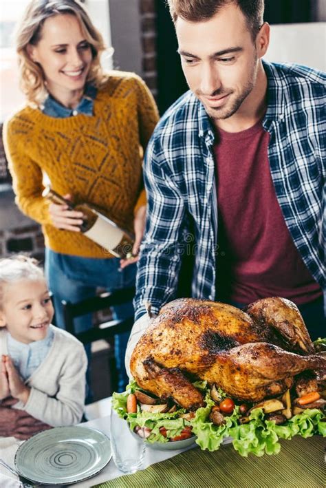 Handsome Young Father Putting Thanksgiving Turkey On Holiday Table