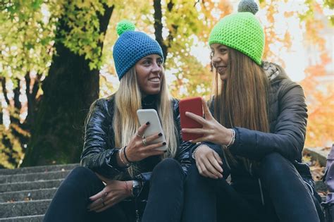 Premium Photo Two Girls Sitting In The Park Using Smartphone Teen Using Mobile Phone Sisters