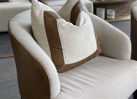 Two Brown And White Pillows Sitting On Top Of A Chair In Front Of A Couch