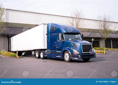 Dark Blue Big Rig Semi Truck With Trailer In Warehouse Dock Load Stock