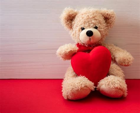 Premium Photo Teddy Bear Holding A Red Heart Sitting On Red Floor