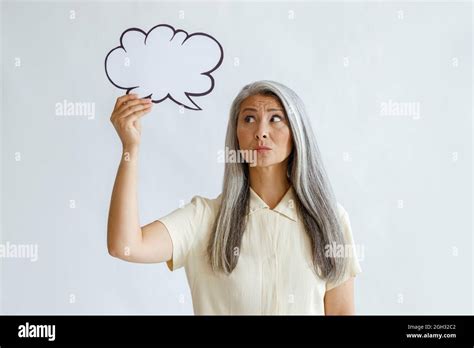 Doubting Mature Woman Holds Blank Text Bubble Standing In Light