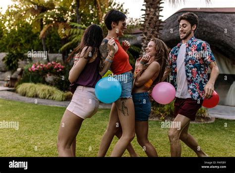 Group Of Friends Playing Balloon Popping Race At Party Men And Women