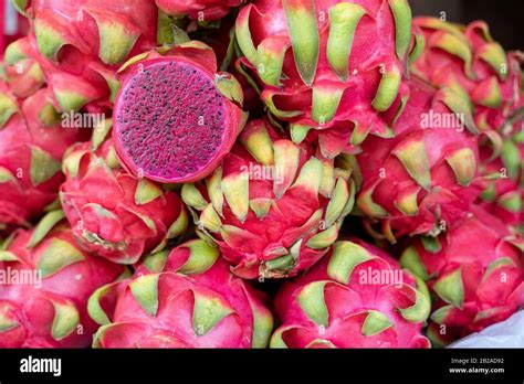 A Cut Dragonfruit On A Pile Of Whole Dragon Fruits For Sale At A Market