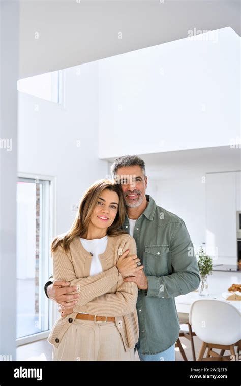 Happy Middle Aged Mature Couple Hugging Standing At Home Vertical