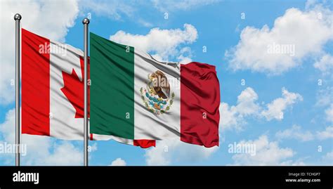 Canada and Mexico flag waving in the wind against white cloudy blue sky ...