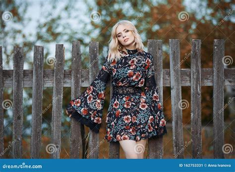 Meisje In Een Mooie Gekleurde Jurk Staat Dicht Bij De Hek In Het Dorp In Het Najaar Blonde Vrouw
