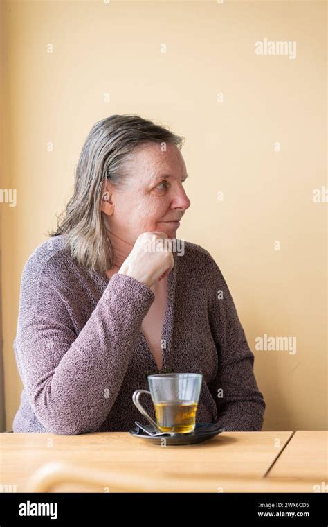Mature Woman Having Tea With A Peach Wall Behind Stock Photo Alamy